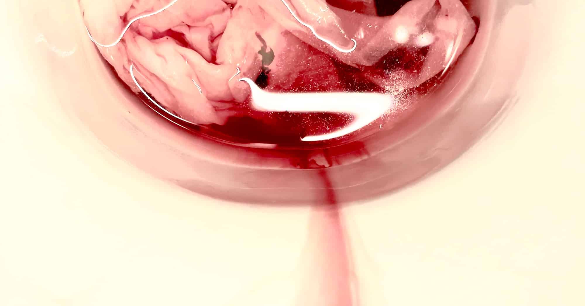 Ästhetische Detail-Fotografie von ins Klo laufendem Menstruationsblut.